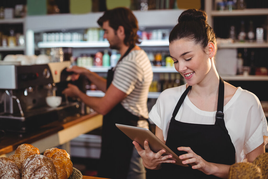 Una cameriera in un bar tiene in mano un tablet