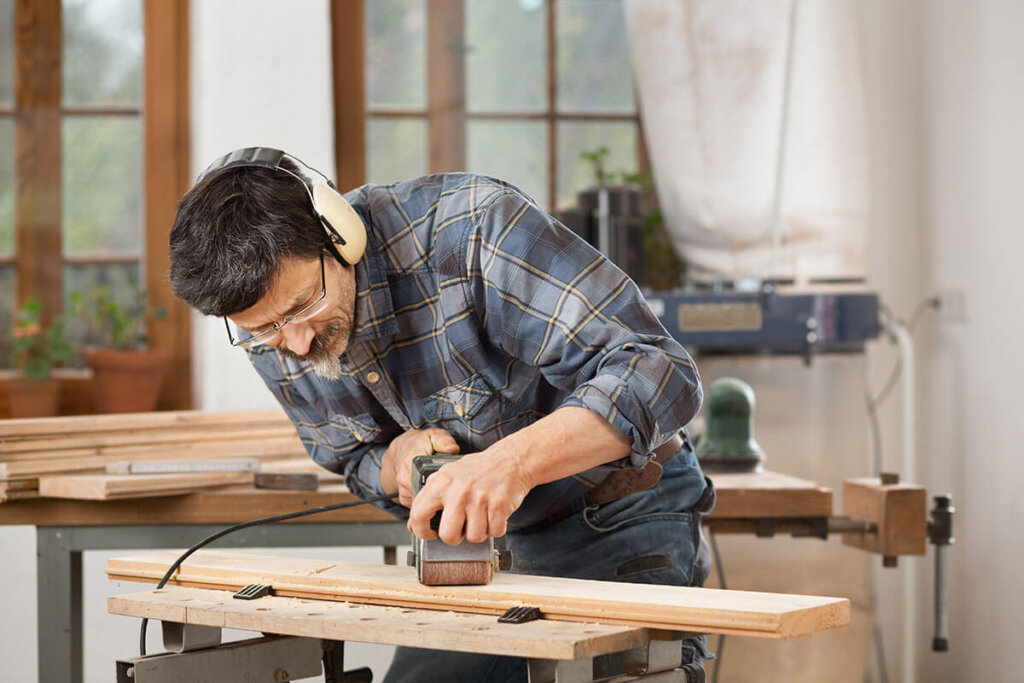 Persona che leviga una tavola di legno