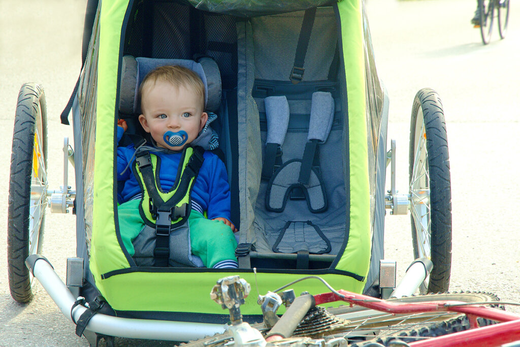 Bambino seduto in un rimorchio per bicicletta verde