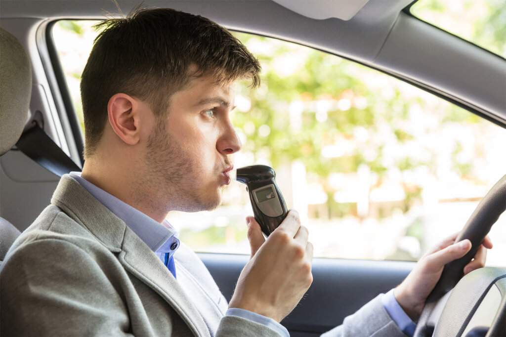 man_sit_in_car_and_uses_breathalyser