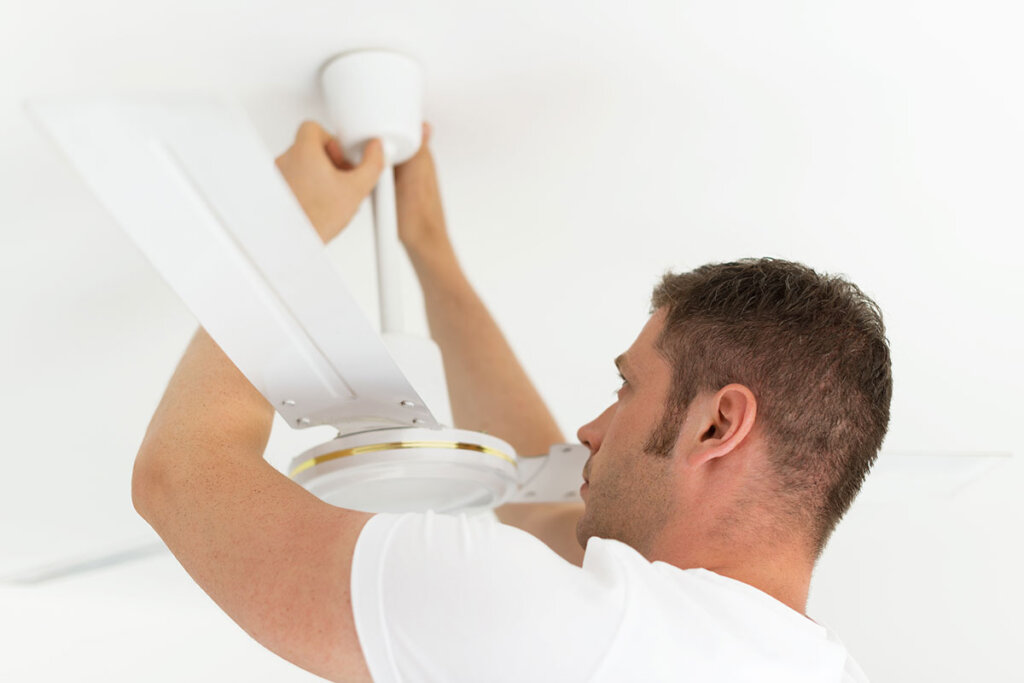 Un uomo installa un ventilatore da soffitto