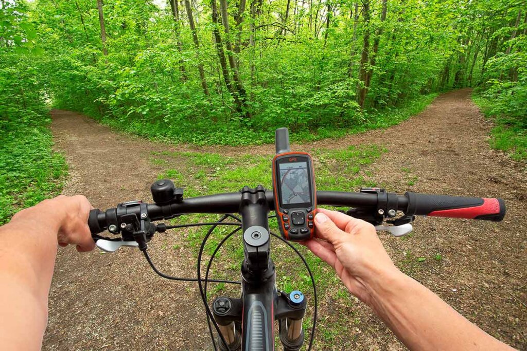 ciclista guarda il suo navigatore prima di attraversare un sentiero nella foresta