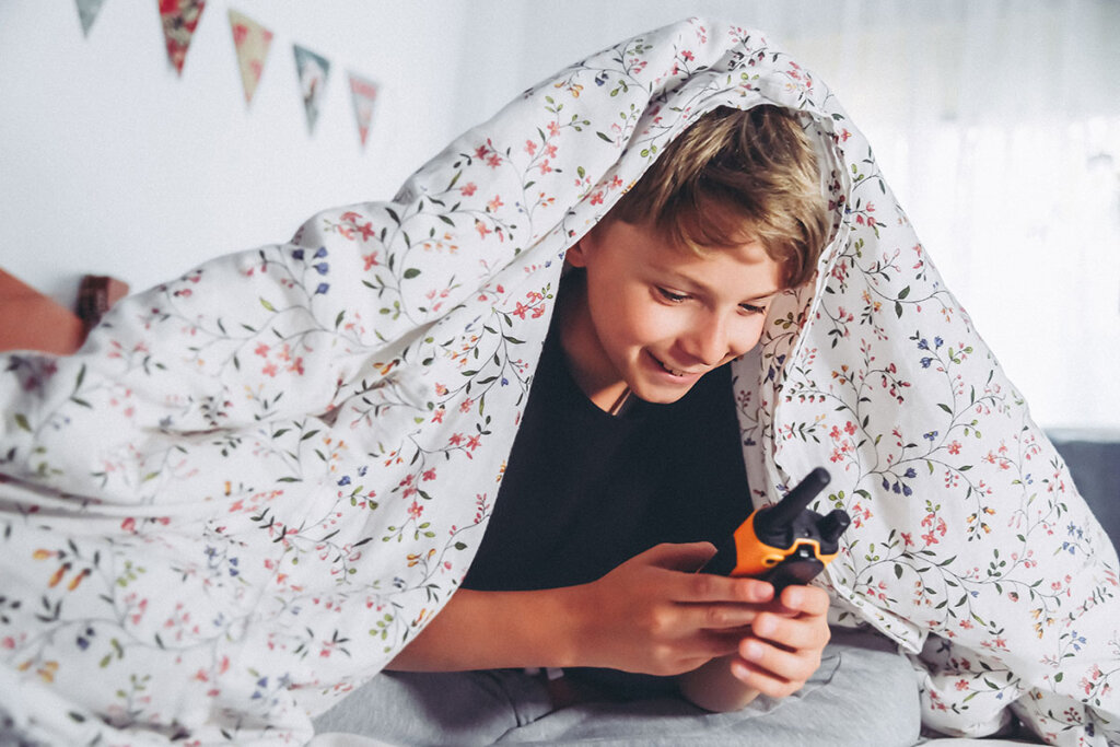 Bambino che gioca con un walkie-talkie a letto