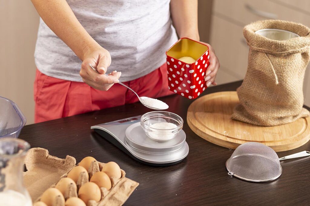 Donna che misura lo zucchero in cucina