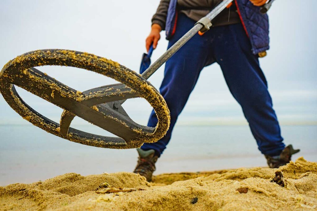 Uomo in piedi sulla sabbia con metal detector