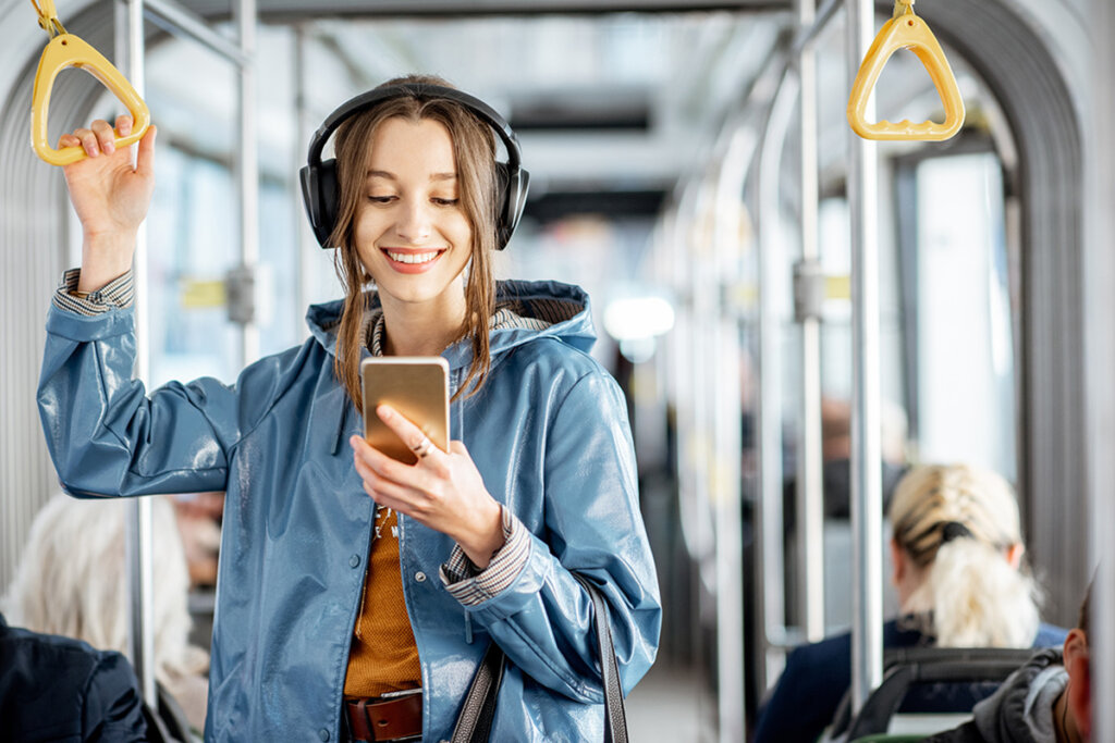 Jonge vrouw op trein met hoofdtelefoon op hoofd