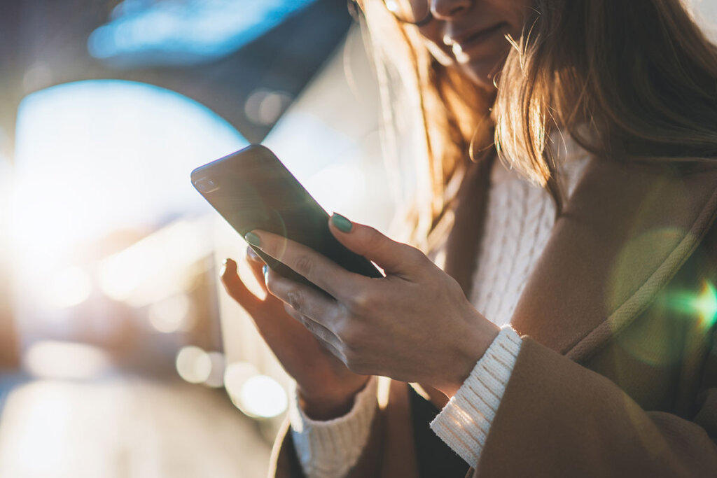 Donna con smartphone in mano alla stazione ferroviaria