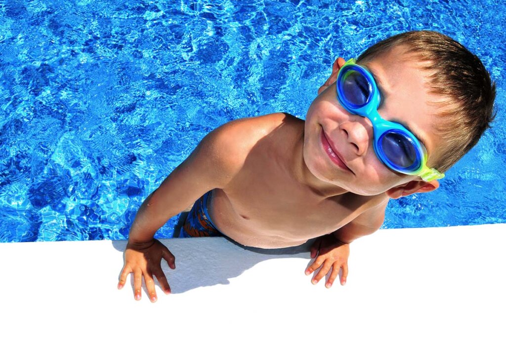 Bambino con occhialini da nuoto esce dalla piscina