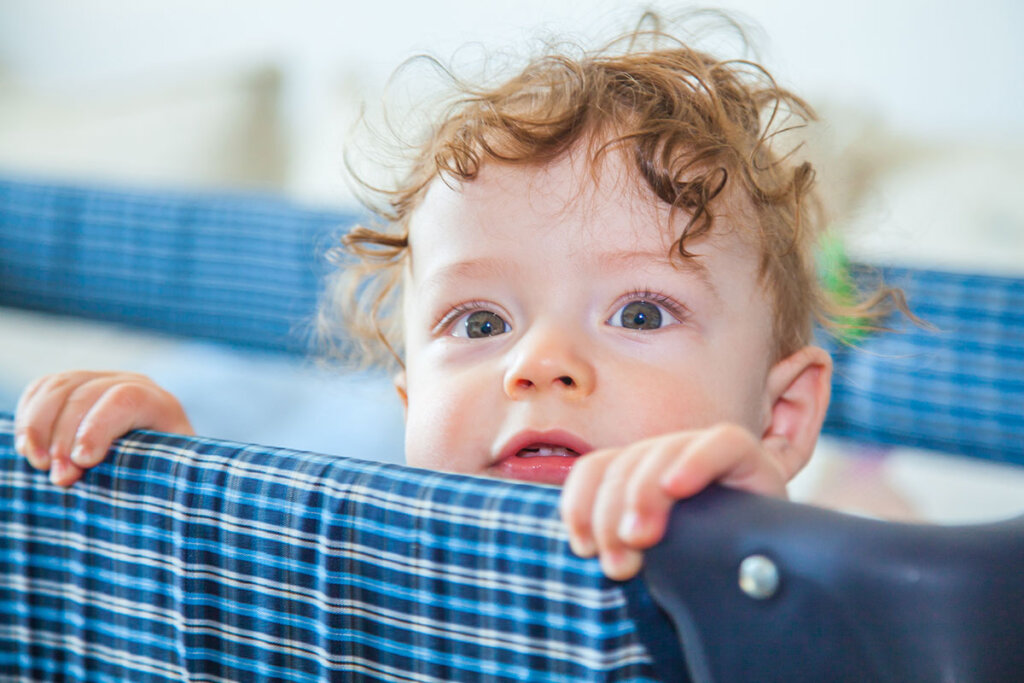 Il bambino nel lettino da viaggio guarda oltre il bordo