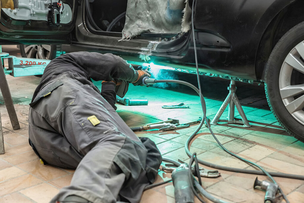 Persona in officina che salda un'auto