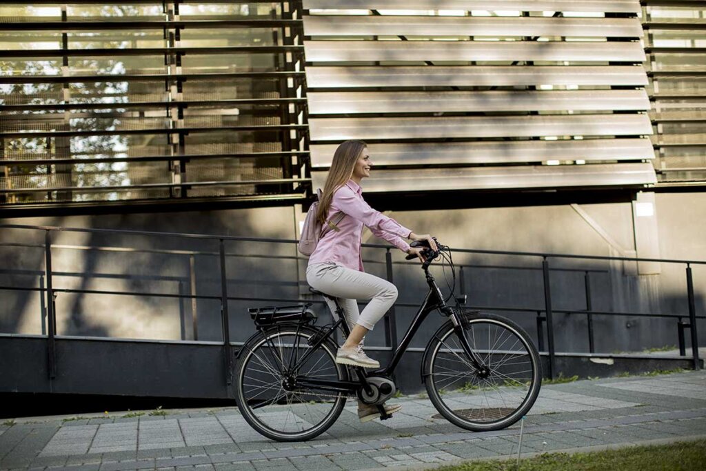 Giovane donna in sella a una e-bike in città